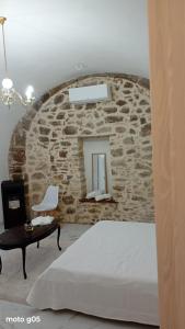 a bedroom with a stone wall with a bed and a chair at La piazza in San Giorgio la Molara
