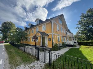 a large yellow building with a black fence at Strandlogiet Ljugarn in Ljugarn