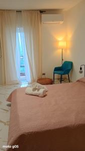 a bedroom with a bed with a blue chair and a window at La piazza in San Giorgio la Molara