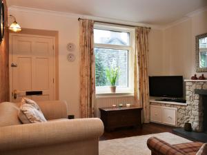 a living room with a couch and a television and a window at Catbells Cottage Keswick in Keswick
