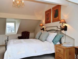 a bedroom with a white bed and a chair at Catbells Cottage Keswick in Keswick +4 photos