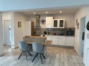 a kitchen with white cabinets and a wooden table and chairs at SleepShop in Nordhausen