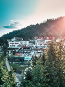 a group of buildings in a city with the sun shining at Hotel Roser House Boutique - pe malul lacului Colibita in Colibiţa