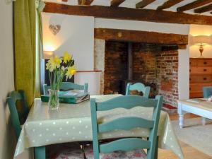 a dining room with a table and chairs and a fireplace at Three Ash Cottage in Bungay