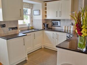 a kitchen with white cabinets and black counter tops at Mainbrace in Port Isaac