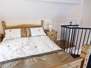 Un dormitorio con una cama con sábanas blancas y una barandilla negra. en Little Barn - Hw7615, en Bettws-yn-Rhôs