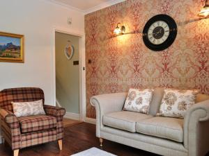 a living room with a couch and a clock on the wall at Catbells Cottage Keswick in Keswick