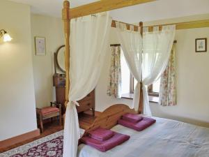 una camera da letto con un letto a baldacchino con due cuscini viola di Strawberie Cottage - E2390 a Stoke Abbott