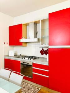 a red kitchen with white appliances and red cabinets at Appartamento Crema centro in Crema