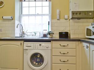 eine Küche mit Spüle und Waschmaschine in der Unterkunft Trentham Cottage in Snettisham