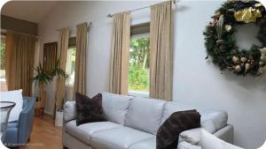 a living room with a white couch and a wreath on the wall at Cozy 4BR 3BA Home- Train to NYC, USOpen, CitiField Mets, Walk to Harbor & Golf in Port Washington +45 photos