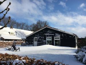Ein schwarzes Gebäude mit Schnee davor. in der Unterkunft Bungalow Buitenlui in Molenschot