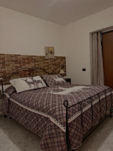 a bed in a bedroom with a brick wall at Camera dell' antico Arco Romano in Pozzuoli
