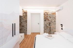two beds in a room with a stone wall at DN ART BLEVIO - APT D first floor with lake view terrace and hot tub in Blevio