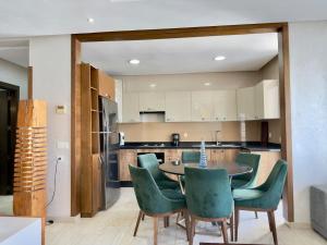 a kitchen with a table and green chairs at Agadir bay luxury in Agadir