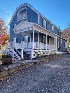 a blue house with a large porch and white railing at Main House - 3 Story 5 Bed 3 Bath Private Deck Courtyard Pet Friendly fee applies in Wolfeboro