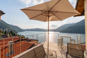 a balcony with an umbrella and a view of a lake at DN ART BLEVIO - APT D first floor with lake view terrace and hot tub in Blevio
