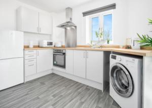 une cuisine avec des armoires blanches et une laveuse et une sécheuse dans l'établissement 2 Bed Apartment - Parking - Sleeps 3 - Netflix 50C, à Sleightholme