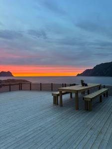 a picnic table on a pier with a sunset at Ocean Panorama in Senja