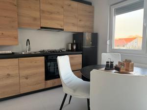a kitchen with a table and white chairs and a counter at Apartman TONKA Vinkovci - novouređeni apartman u centru Vinkovaca in Vinkovci