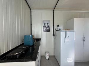 a kitchen with a black counter and a white refrigerator at Charmoso e bem localizado! in Tijucas +28 photos