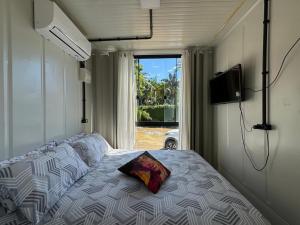 a bedroom with a bed with a pillow and a window at Charmoso e bem localizado! in Tijucas +19 photos