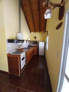 une cuisine avec une cuisinière et un réfrigérateur dans l'établissement Cabañas Alünmew, à Juana Koslay 