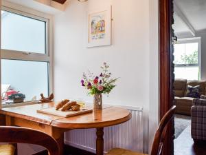 a dining room table with a vase of flowers on it at Ty Lewis Cottage in Llanelli +16 photos