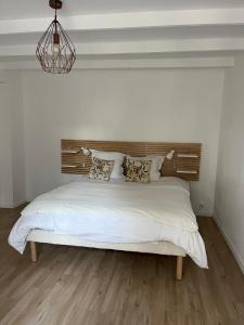 une chambre avec un grand lit blanc avec une tête de lit en bois dans l'établissement Lamaisondubois31, à Pibrac