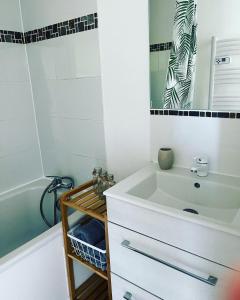 une salle de bain avec un lavabo, une baignoire et un miroir dans l'établissement Lamaisondubois31, à Pibrac
