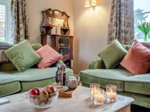 a living room with green couches and a table with a bowl of fruit at Hill Farm in Blyford +31 photos