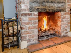 a brick fireplace with a fire in it at The Smithy - E5445 in Brassington +31 photos