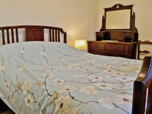a bed with a blue blanket with white flowers on it at Is Helen Cottage in Caernarfon