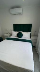 a large white bed with a green headboard in a bedroom at The M GuestHouse in Kempton Park