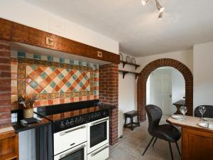a kitchen with an oven and a table with a chair at Dolwen Isaf in Llangadfan