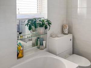 La salle de bains est pourvue d'un lavabo blanc et d'une plante. dans l'établissement Lavender Cottage, à Frinton-on-Sea