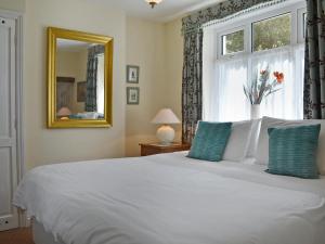 a bedroom with a white bed and a window at Nell's Cottage in Askam in Furness