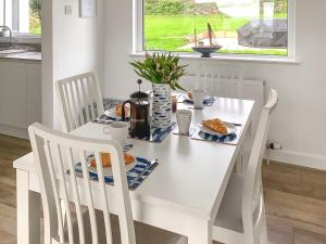 a white dining room table with two chairs and a table with food at Blue Horizon in Sidmouth