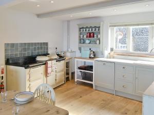 une cuisine avec des armoires blanches et une table en bois dans l'établissement Turnstone Cottage, à Sheringham