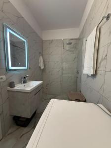 a white bathroom with a sink and a mirror at Luxury Apartment Orikum in Orikum