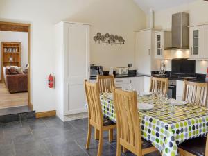 a dining room with a table and chairs and a kitchen at Sgubor Ucha in Trefriw