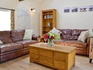 a living room with a couch and a table with flowers on it at Sgubor Ucha in Trefriw
