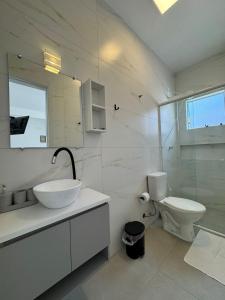 a white bathroom with a sink and a toilet at Apto térreo em Tijucas n 04 in Tijucas