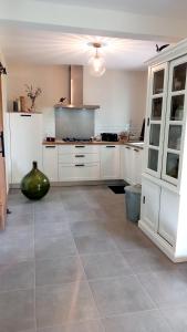 Una cocina con gabinetes blancos y piso de baldosas. en BOCENNO Catherine, en Ambon 1 foto más