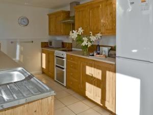 eine Küche mit Holzschränken und einem weißen Kühlschrank in der Unterkunft Granny Bond's Farmhouse in Buckland Brewer