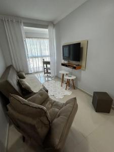 ein Wohnzimmer mit Couch und Flachbildfernseher in der Unterkunft AP Novinho! à 150m das piscinas! 3 ar cond - churrasqueira in Piratuba