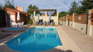 a swimming pool with chairs and a house at Cabañas Alünmew in Juana Koslay 