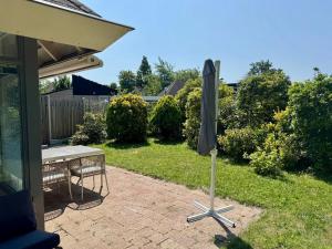 a patio with a table and an umbrella in the yard at Villa Dune I in Ouddorp