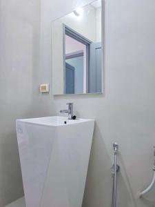 a white bathroom with a sink and a mirror at Tezdaine's garden in Bin Rhilouf