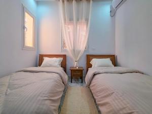 two beds in a room with a window at Tezdaine's garden in Bin Rhilouf +50 photos